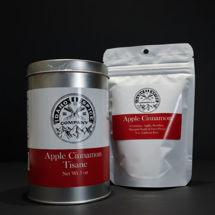 Silver canister and white bag of Apple Cinnamon Tisane from IDY Hot Spice Company on a black background