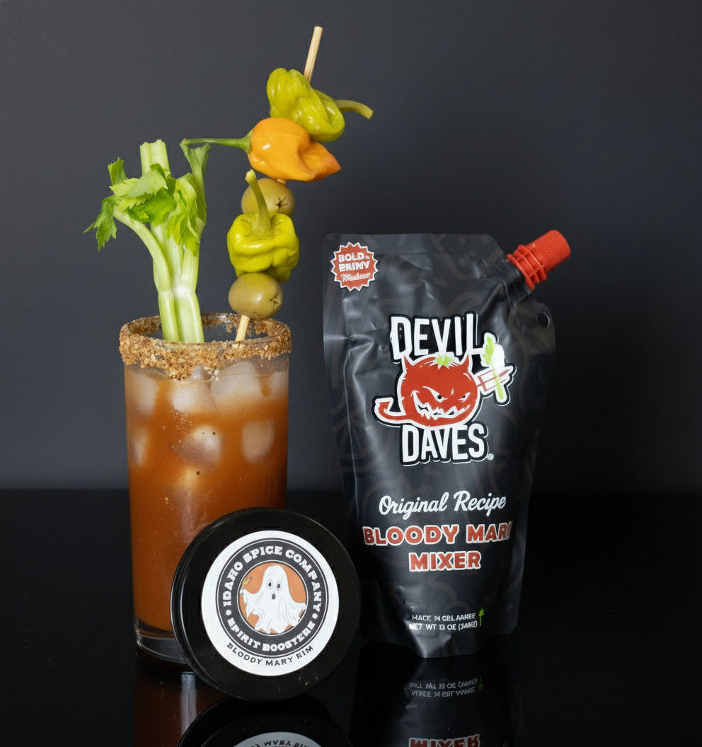 Bloody Mary cocktail with garnishes and Devil Dave's Bloody Mary mixer on a wooden surface.