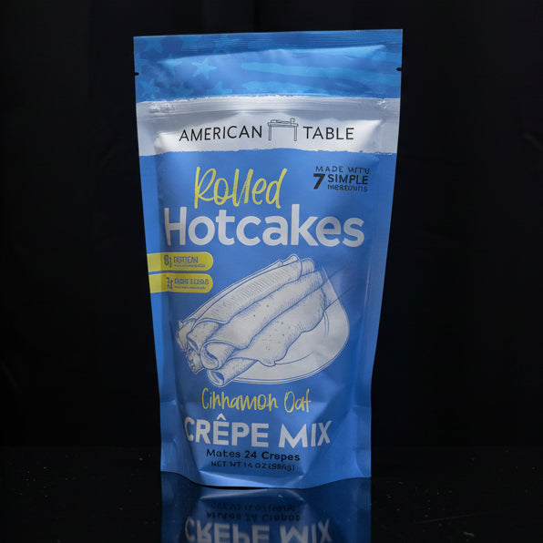 Blue package of American Table Rolled Hotcakes Creèpe Mix on a wooden surface with a black background