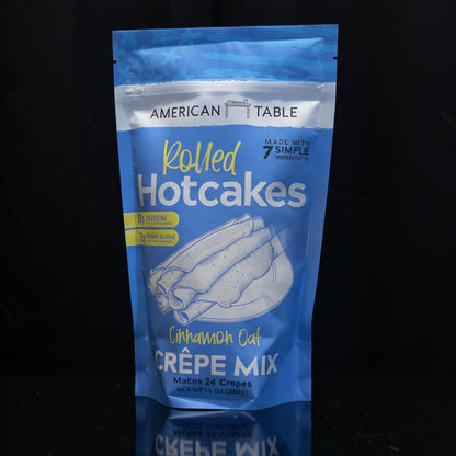 Blue package of American Table Rolled Hotcakes Creèpe Mix on a wooden surface with a black background