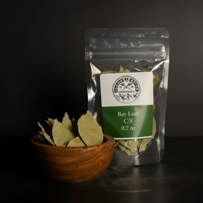 Bay leaf package with a bowl of bay leaves on a dark surface