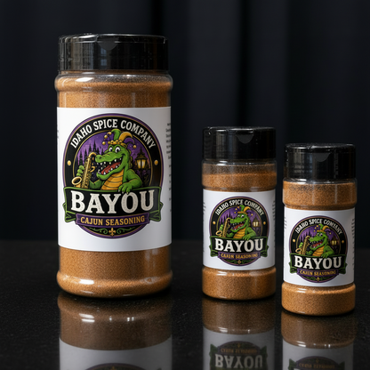 Three jars of Idaho Spice Company Bayou Cajun Seasoning on a reflective surface with a dark background.