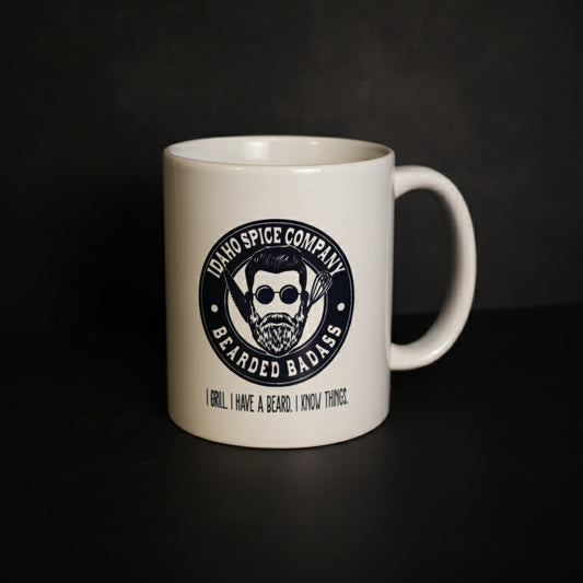 White mug with a black logo and text on a dark surface and gray background