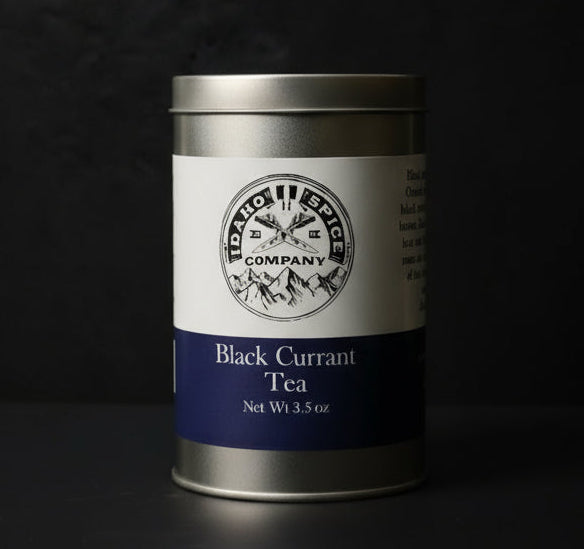 Silver canister of Black Currant Tea with a label on a dark background