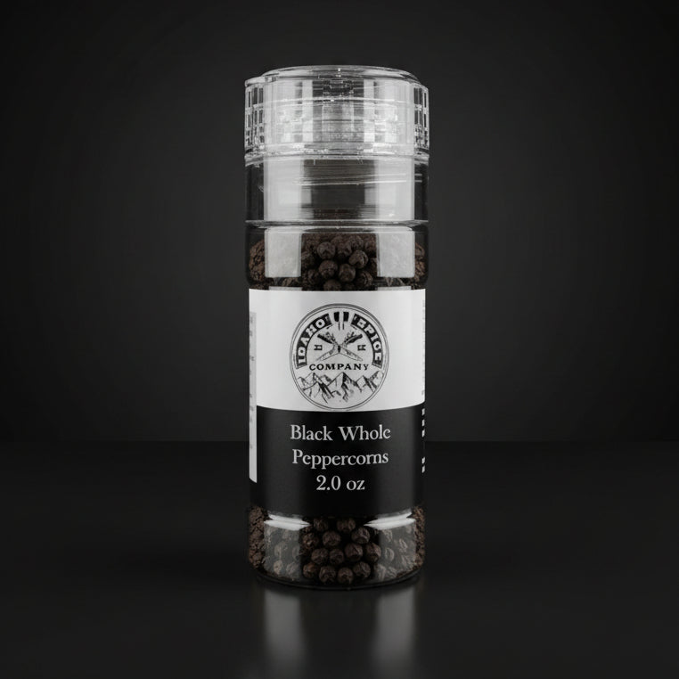 Bottle of black whole peppercorns on a wooden surface with a dark background