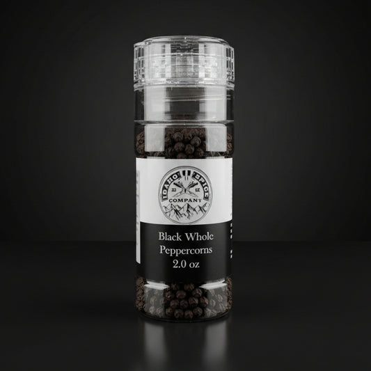 Bottle of black whole peppercorns on a wooden surface with a dark background