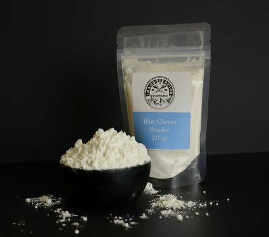 Bag of blue cheese powder with a scoop of powder on a dark surface