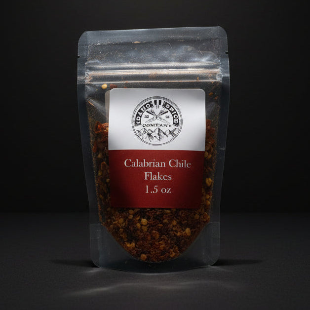 Packaged Calabrian Chili Flakes on a wooden surface with a black background