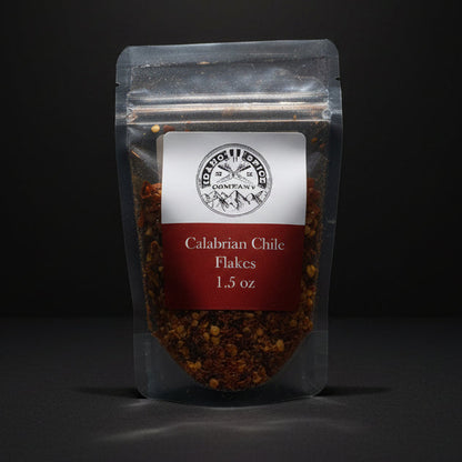 Packaged Calabrian Chili Flakes on a wooden surface with a black background