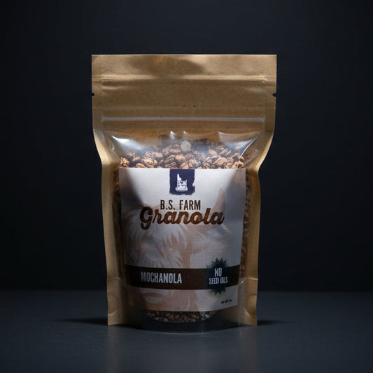 Bag of B.S. Farm Granola on a wooden surface with a dark background